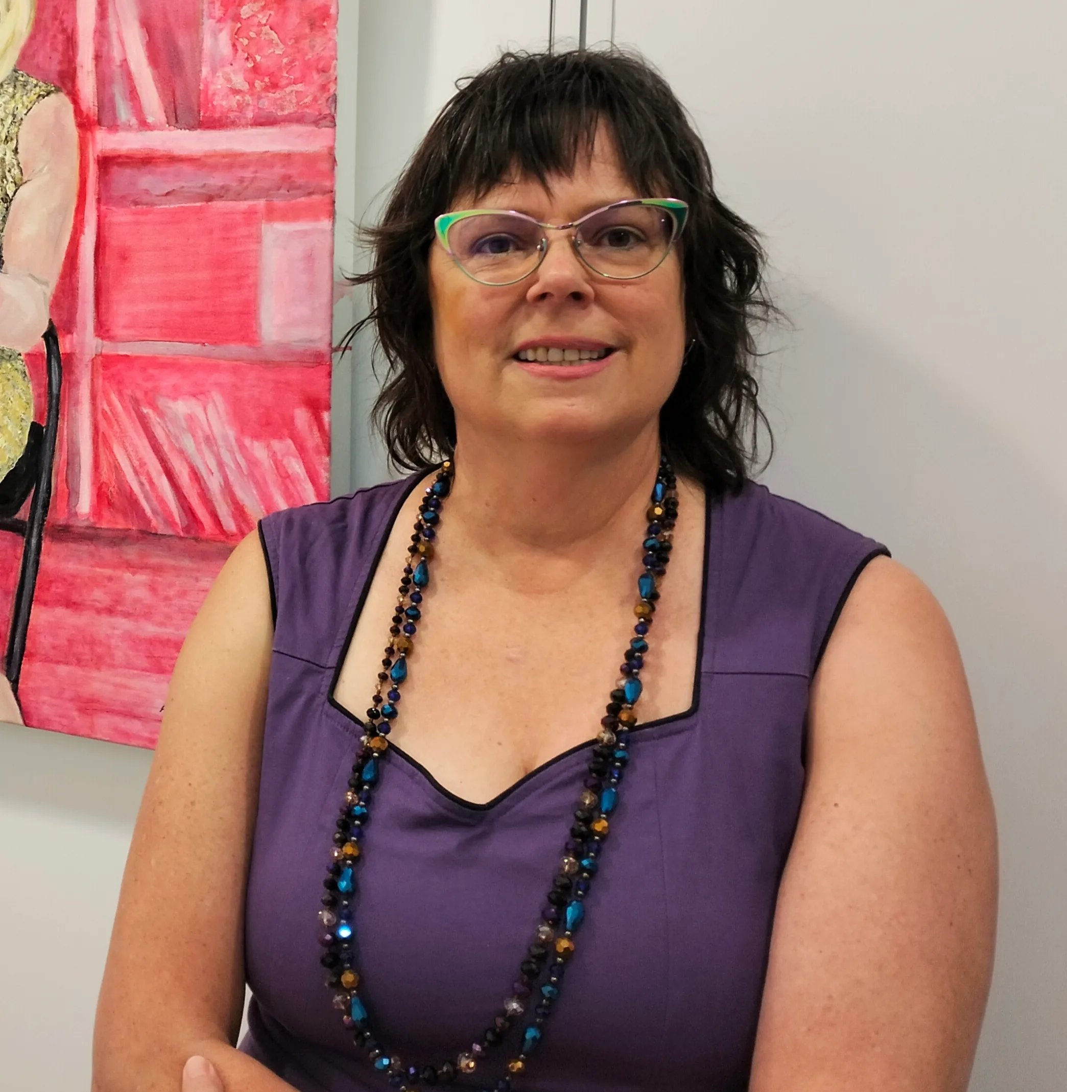 woman in glasses purple top and black necklace