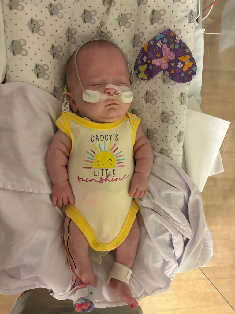 Image of baby in hospital wearing yellow onesie