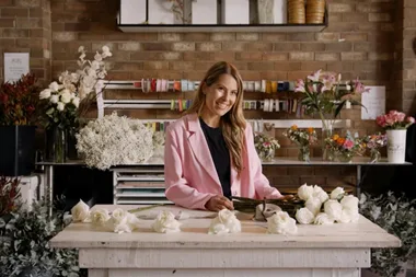 Image of woman wearing pink blazer standing behind counter of florists