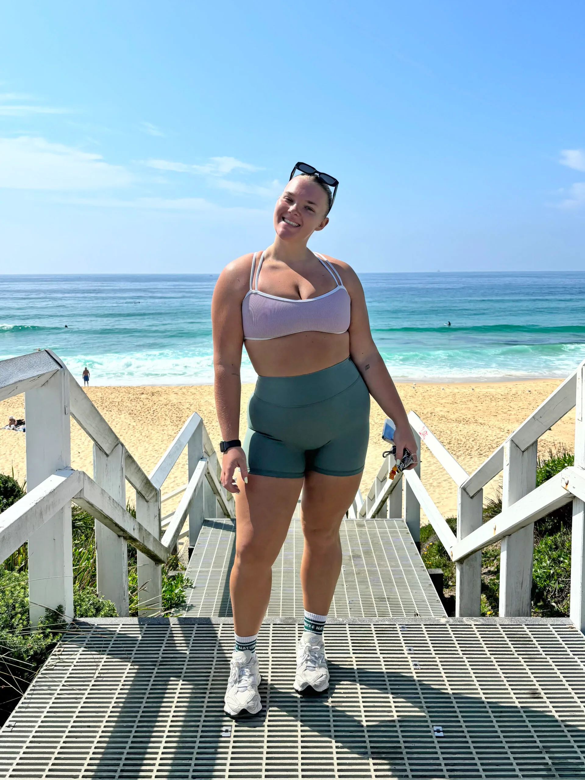 Chloe is standing in front of the beach in activewear