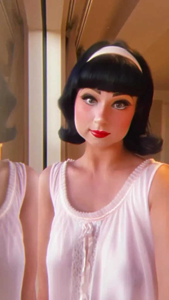 Rochelle in 50s make up. She wears a pink band in her hair to match a pink babydoll dress