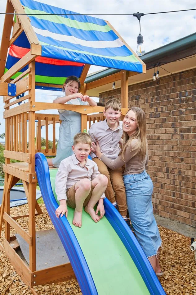 Image of mum and three children diagnosed with childhood dementia on slippery dip