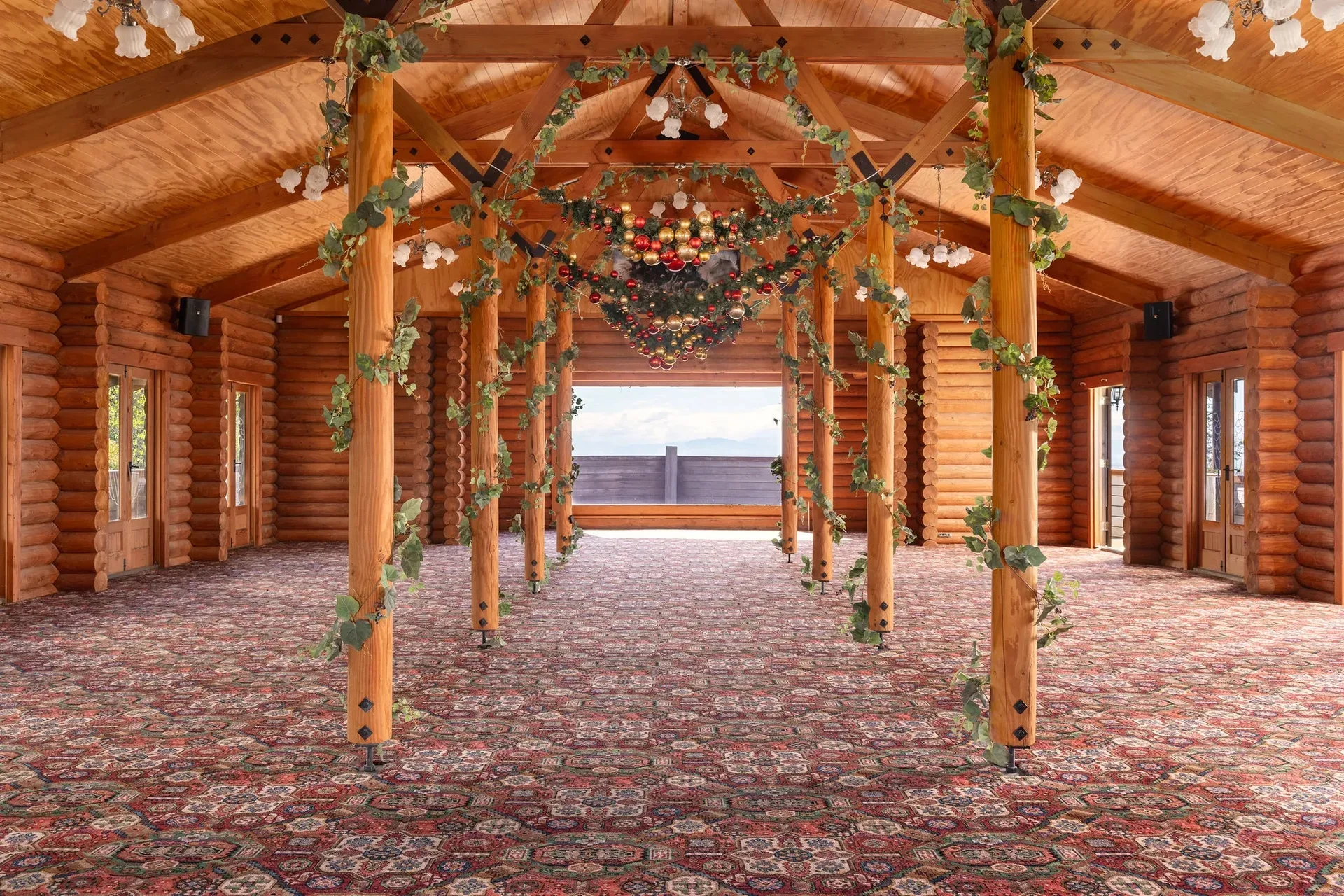 A hall with wooden poles decorated with green garlands