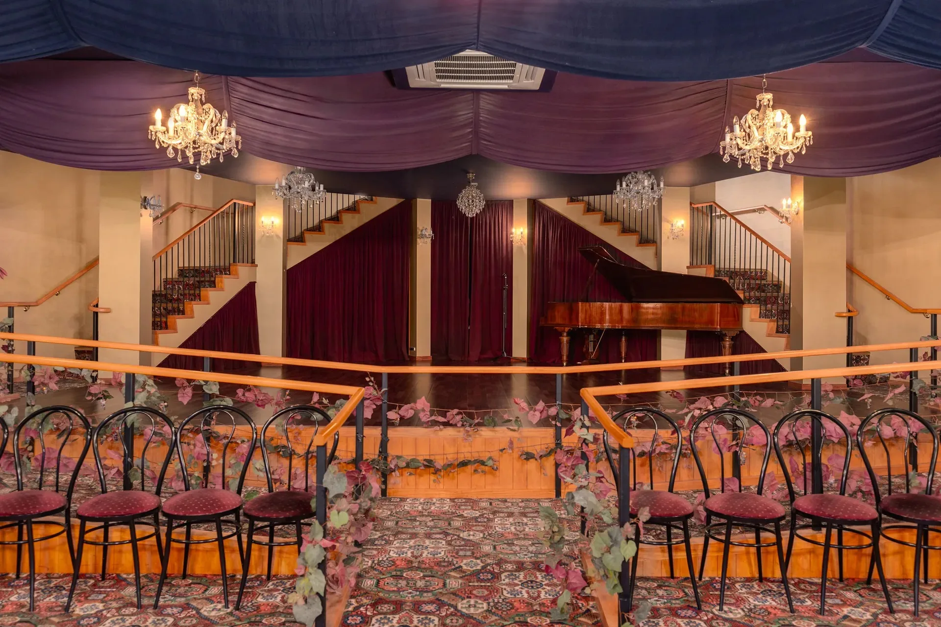 Stage with seats in front and chandeliers above inside the wooden structure