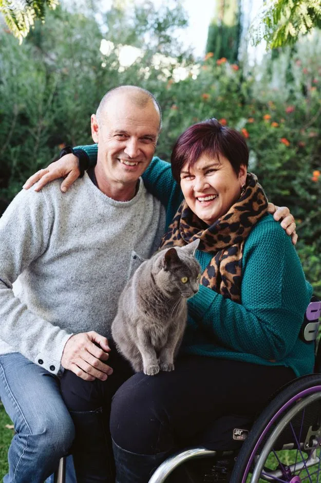 Image of man, woman in wheelchair and grey cat