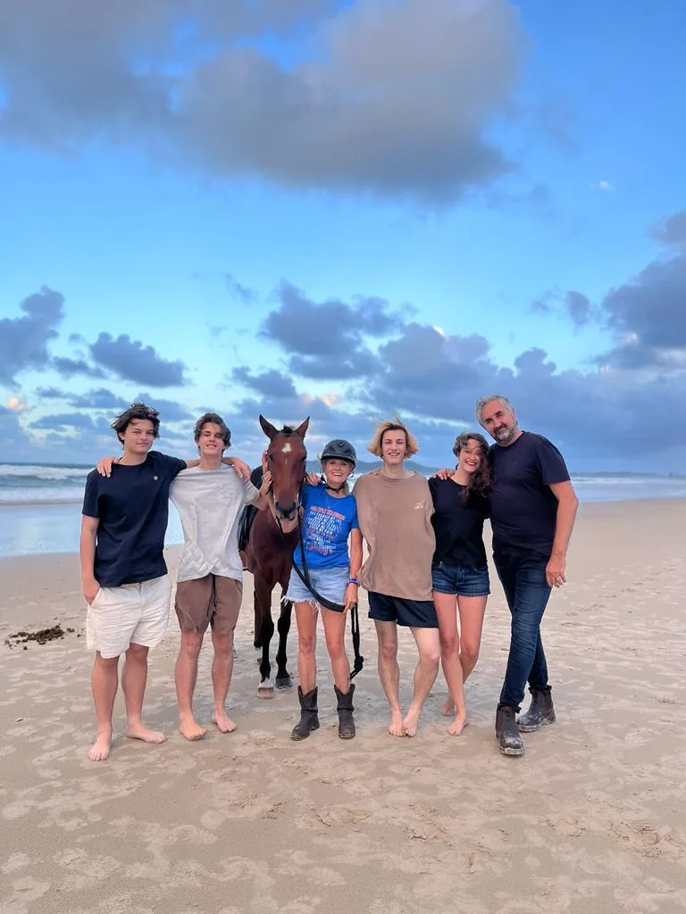 Claire and John with their children standing on the beach with Claire's horse.