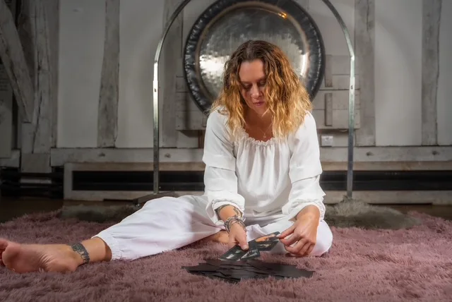 woman in white trousers and white top dealing out tarot cards