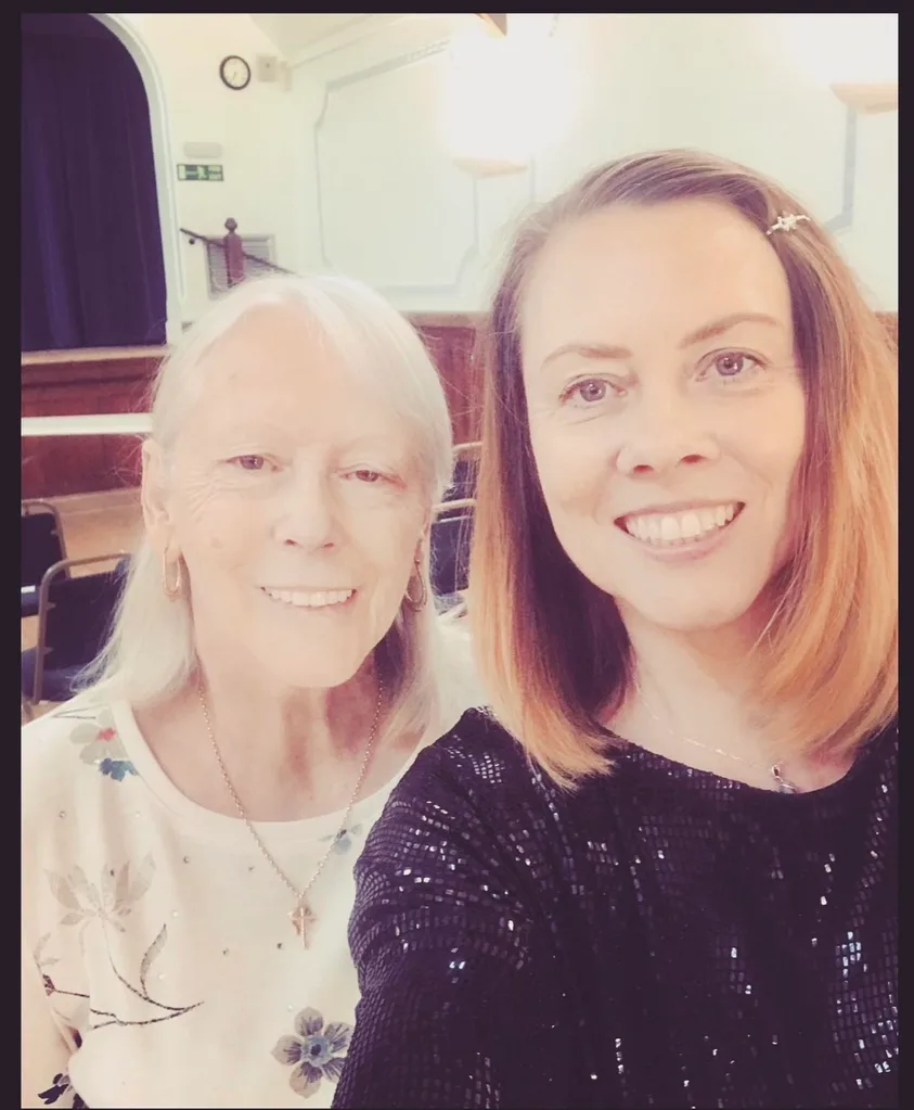 woman in white top and woman in black top stood together.