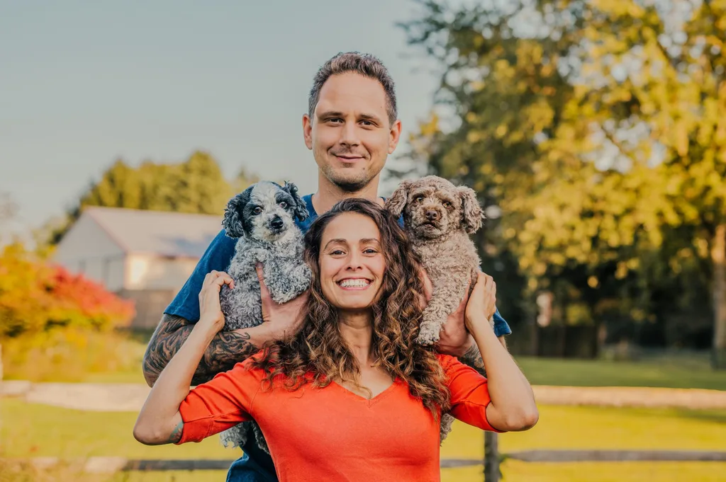 Image of man and woman holding two poodle dogs