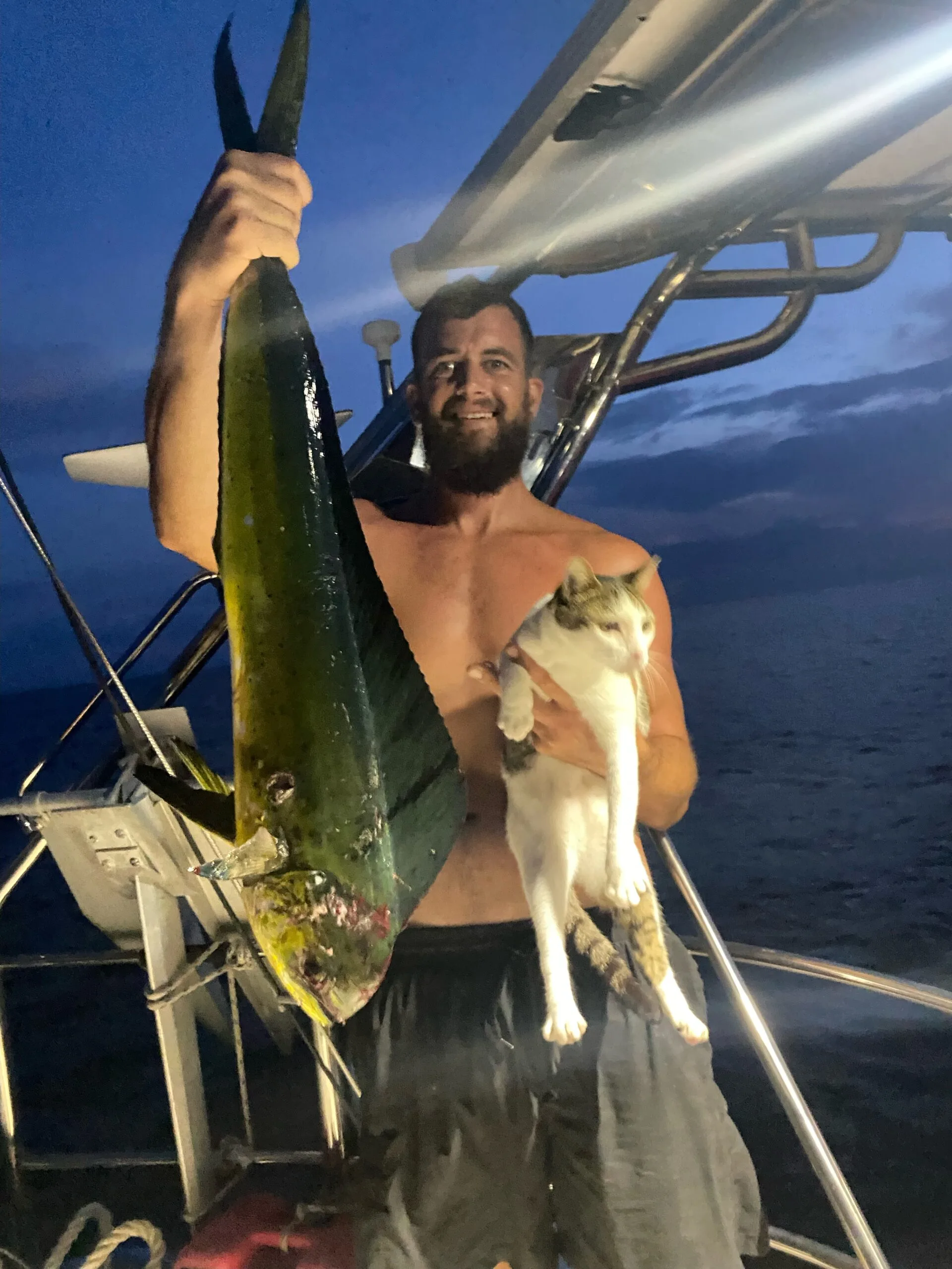 man holds big fish in left hand and cat in right hand