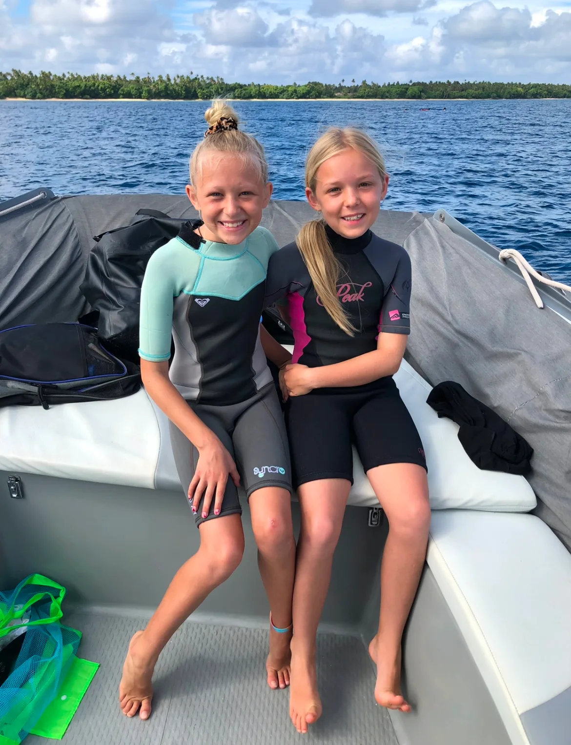 Carmen Ellis' daughters Mackenzie and Harper sitting on a boat in their wetsuits