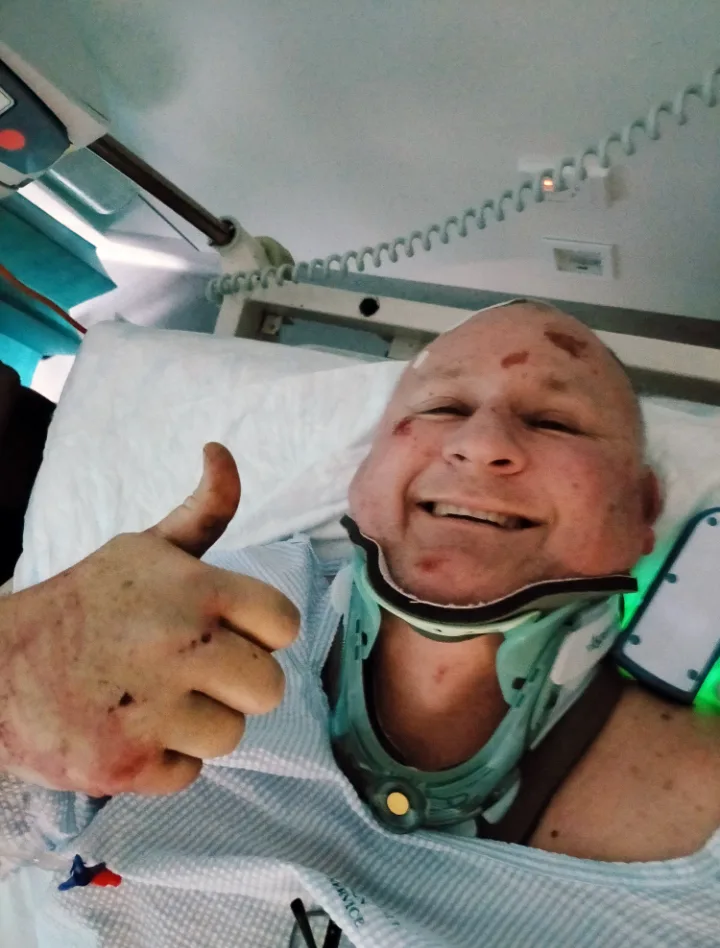 man in hospital with neck brace giving thumbs up sign