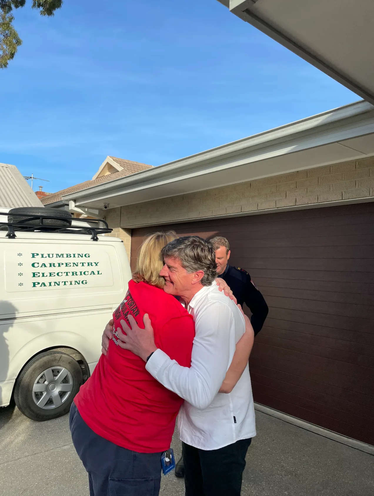 man in white shirt hugging woman in red