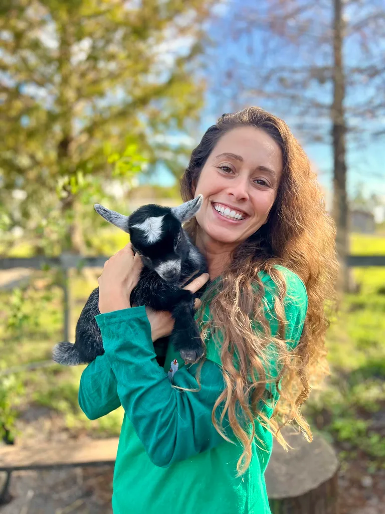 Image of woman wearing green top and holding a lamb