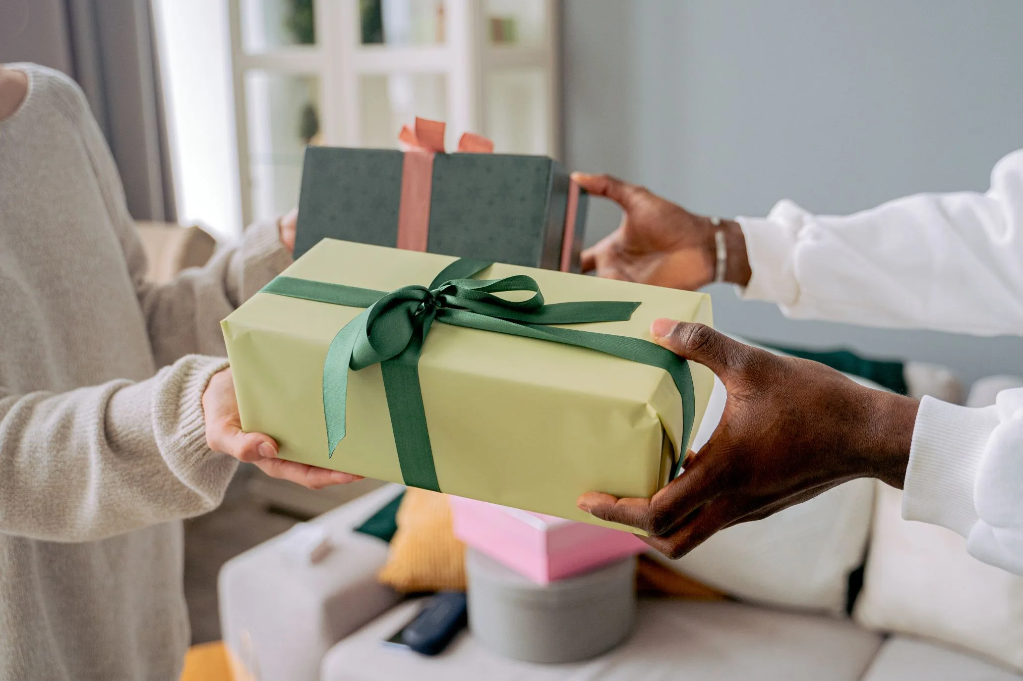 Hands passing a wrapped gift to another pair of hands