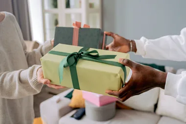 Hands passing a wrapped gift to another pair of hands