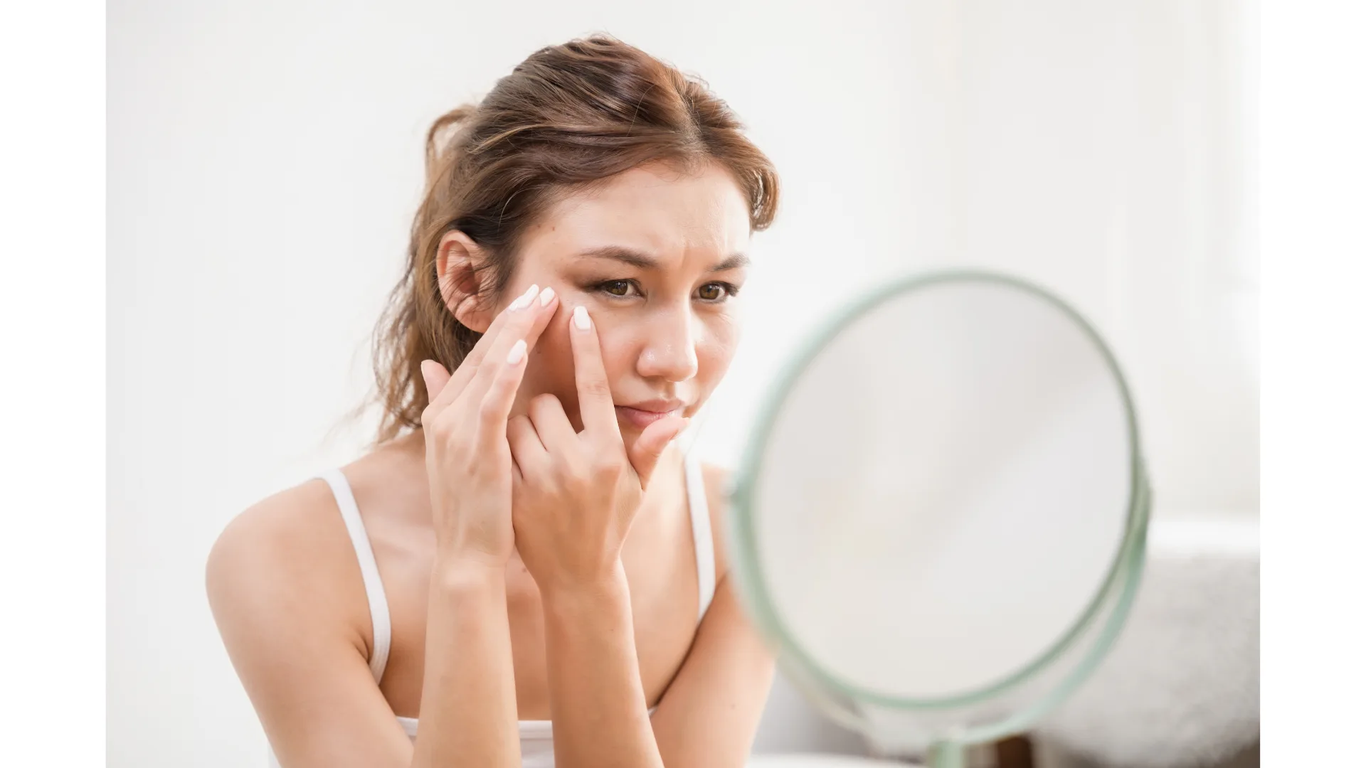 A woman inspects her skin in a mirror.