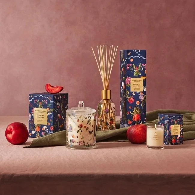 still life product picture of candles and scented products against a maroon background