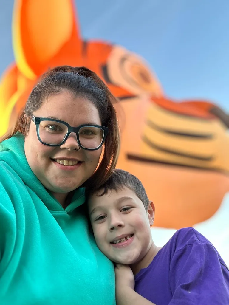 Woman in Blue top and boy in Purple top with Tiger balloon in background
