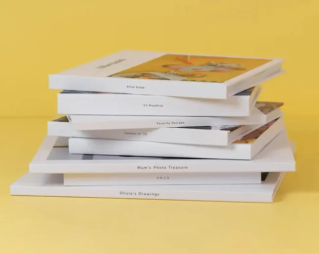 Stack of customised photobooks against a yellow background