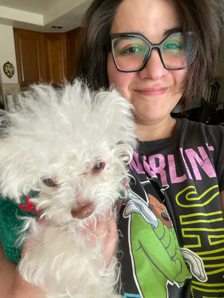 White fluffy dog with his owner. She is wearing a black t-shirt and black glasses