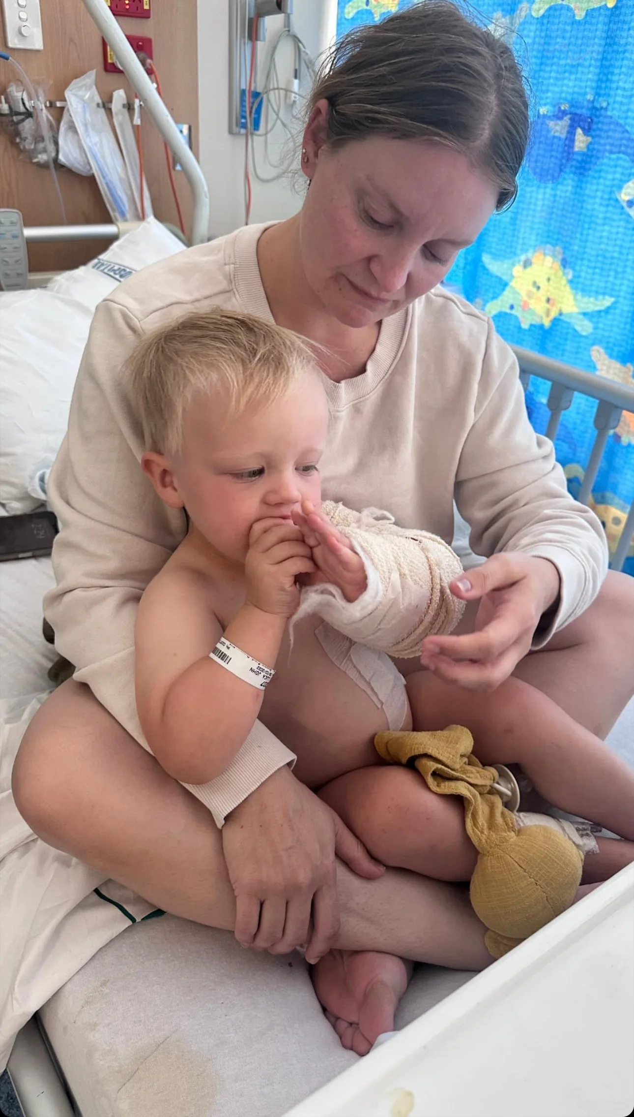 little boy cradled in mums arms. he is in hospital 