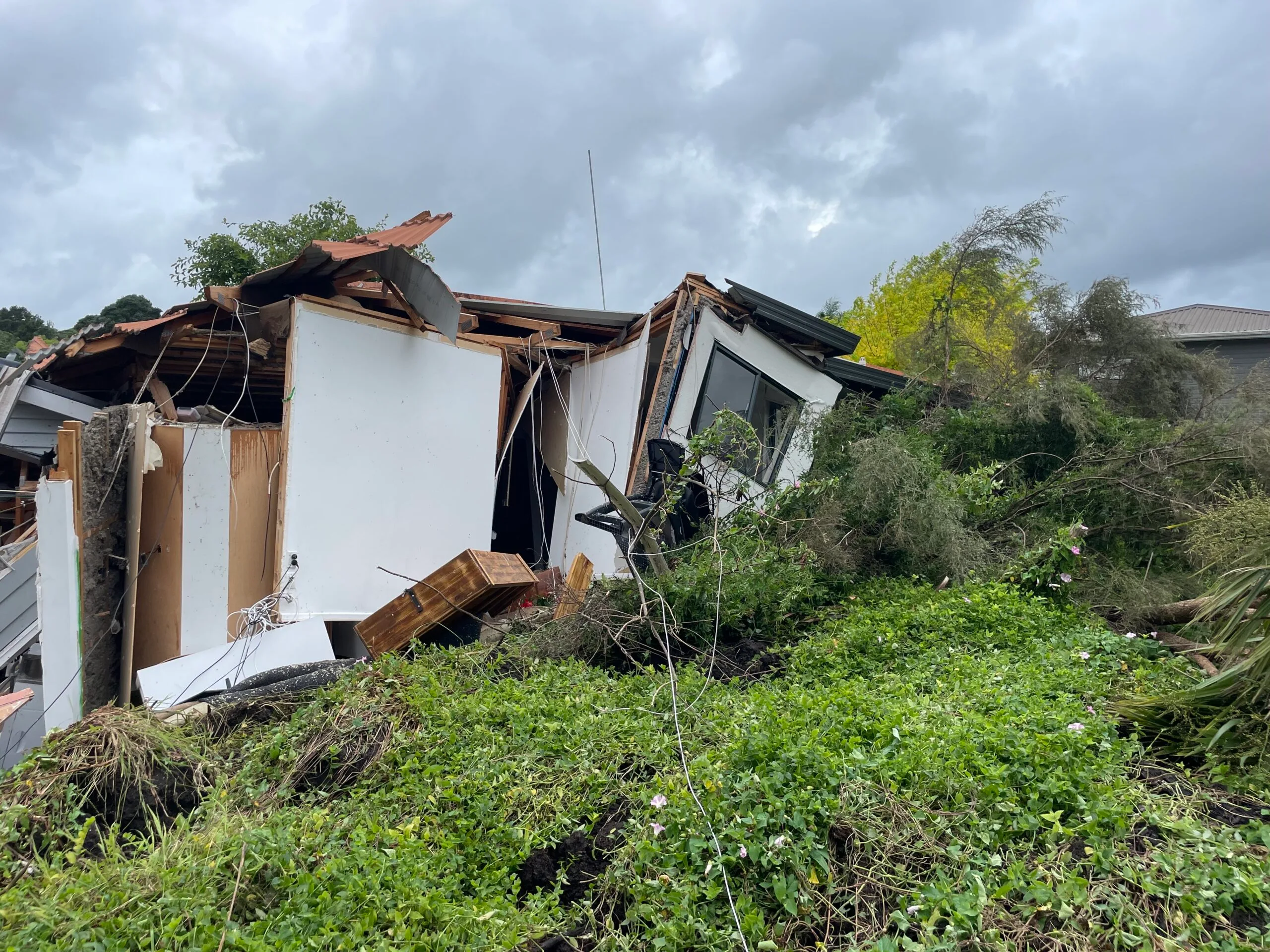 white house demolished by landslide of trees grass and mud