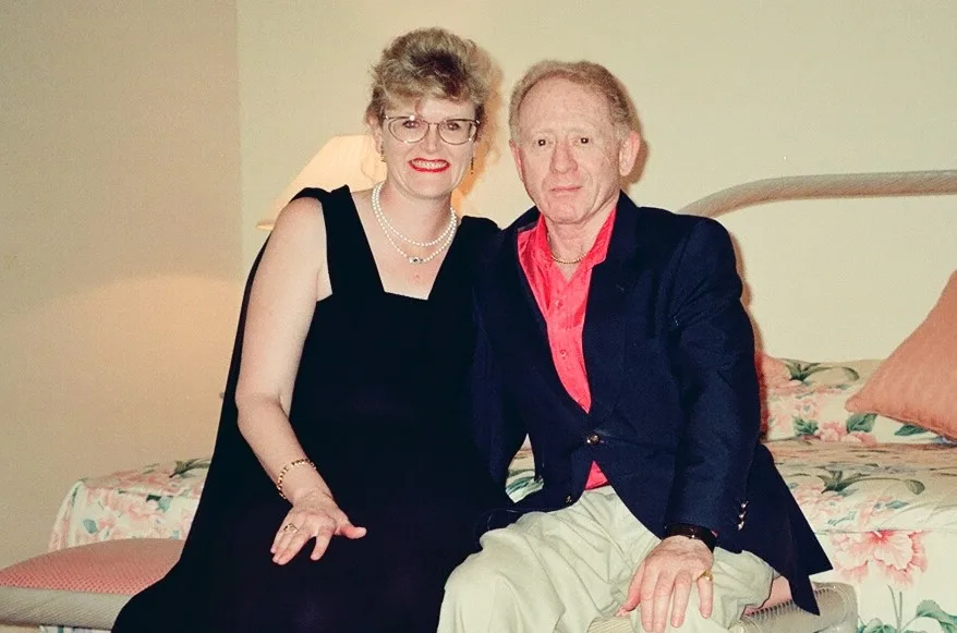 man and woman sit together on bed