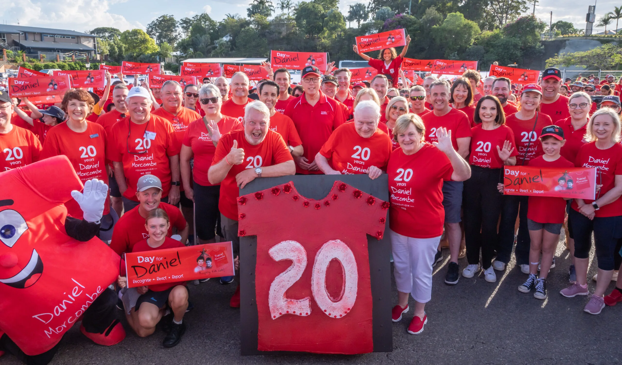 People in red tshirts holding a sign reading 20 