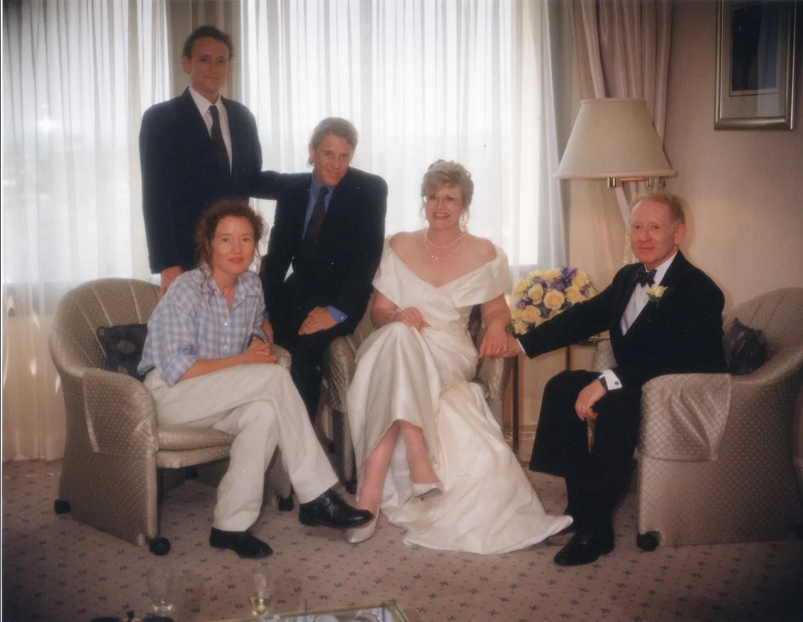 Woman in white dress with man in suit surrounded by friends