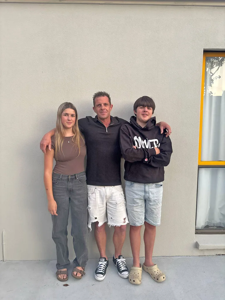 Man in black top white shorts, girl in grey trousres and brown top and boy in black tshirt and jean shirts