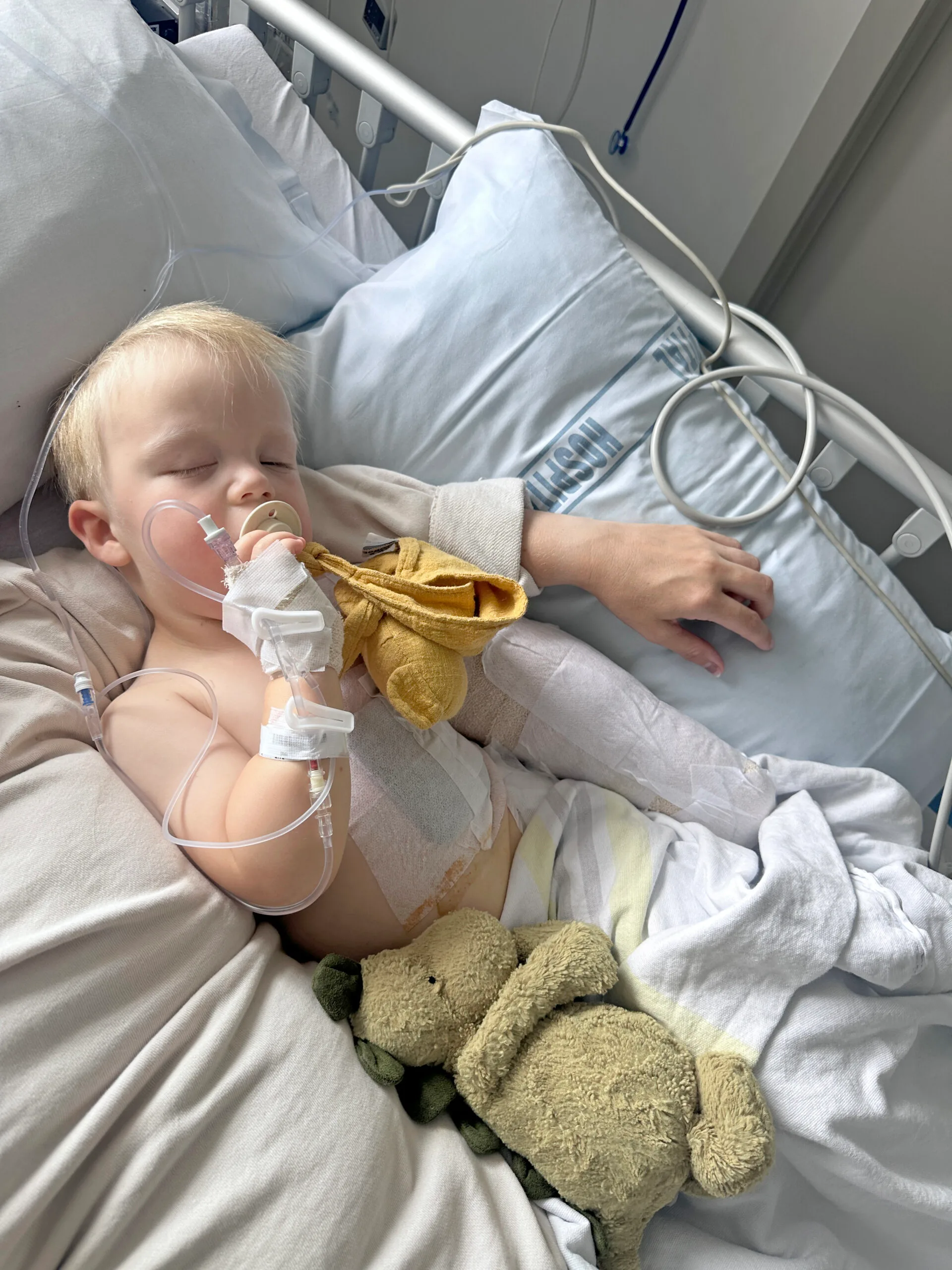 young boy in hospital bed with arm wrappped in white bandages