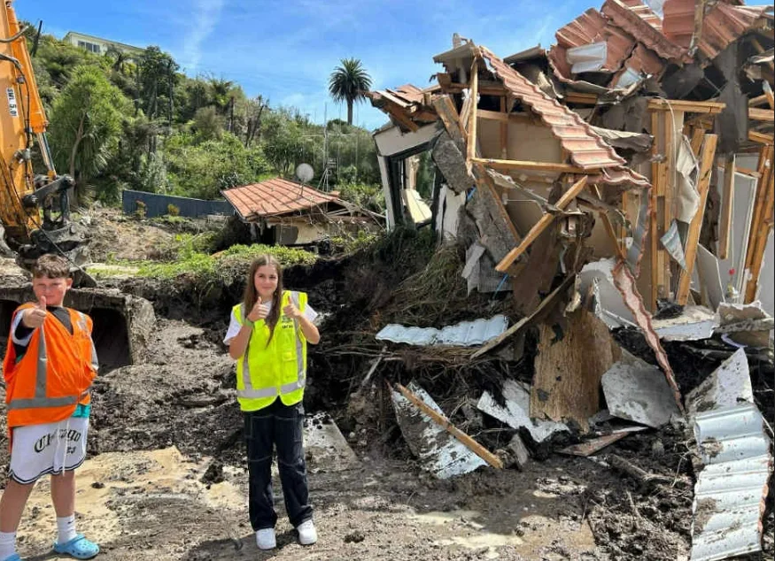 girl in fluro vest outside of demolished house