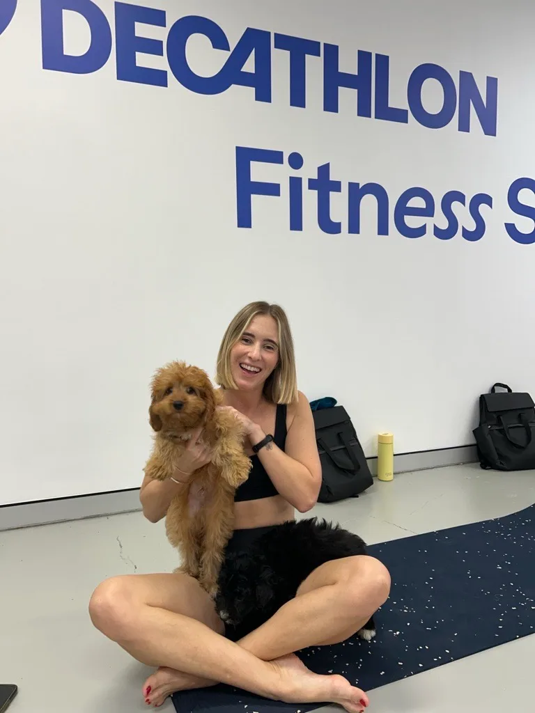 girl in black activewear cuddling small tan dog