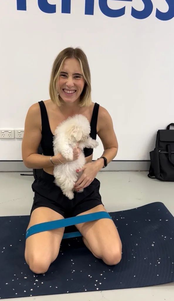 girl in black workout gear holding white puppy