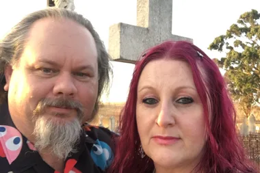 Man and woman smile for the camera. He is wearing a black pac-man shirt.