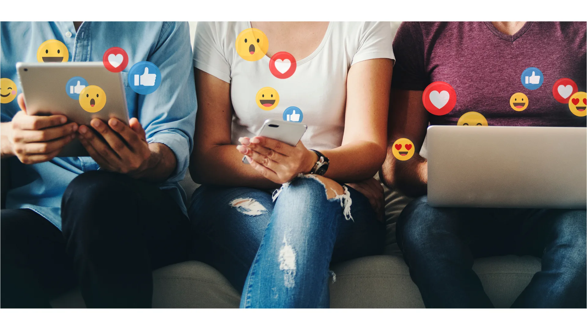 Three anonymous people sit side-by-side while staring at their devices as emojis float off their screens.