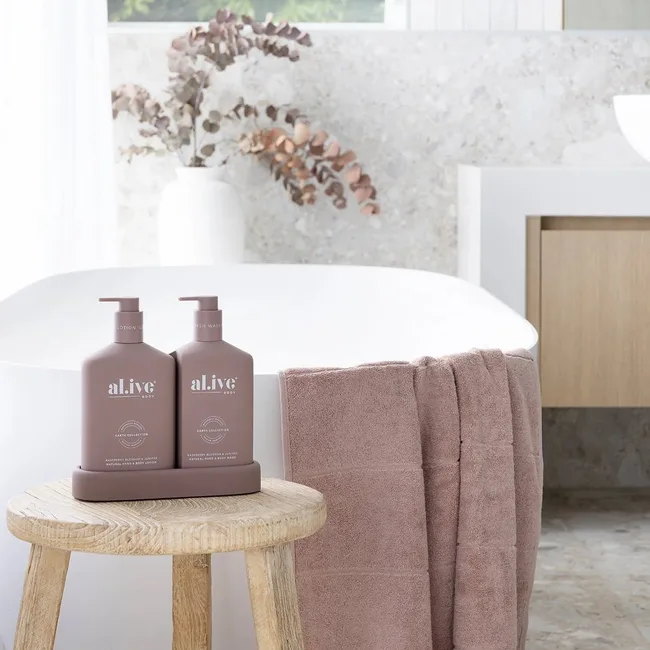 Dusty purple body wash set next to white bathtub with pink towel