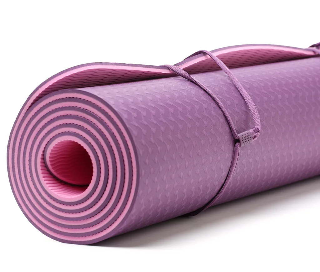 A pink yoga mat is rolled tightly