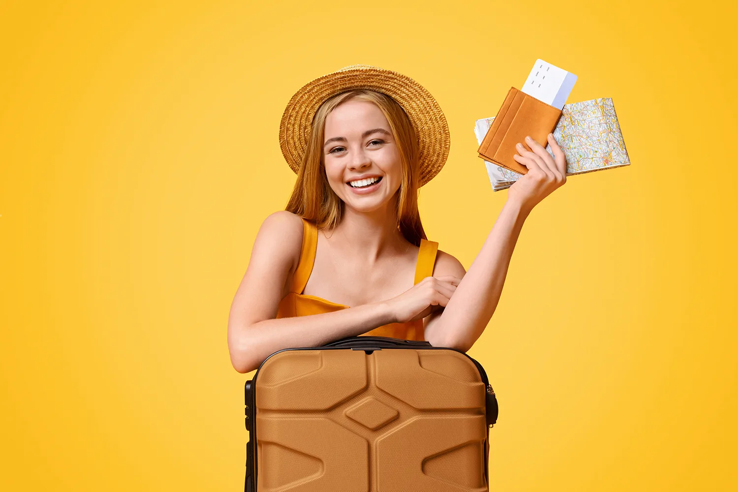 Happy girl tourist lean on suitcase and holding flight tickets and map, ready to travel, posing over yellow background with copy space