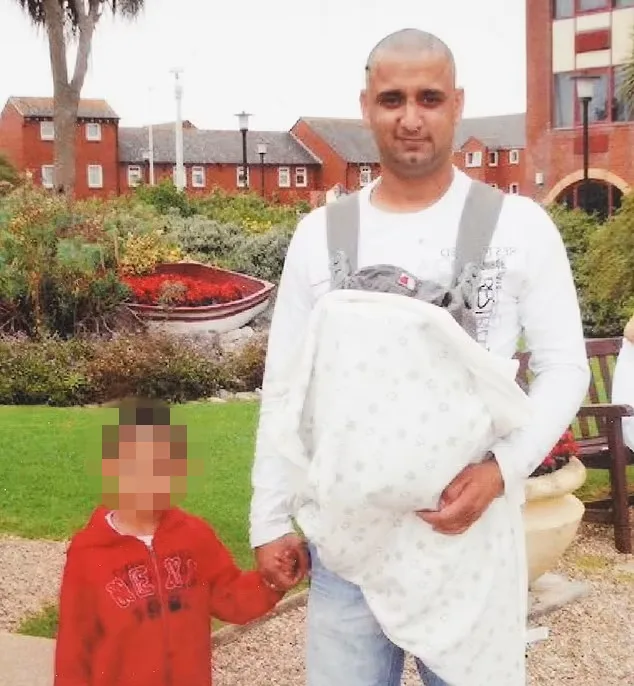 dad wearing white shirt with baby carrier on, holding sons hand in red shirt