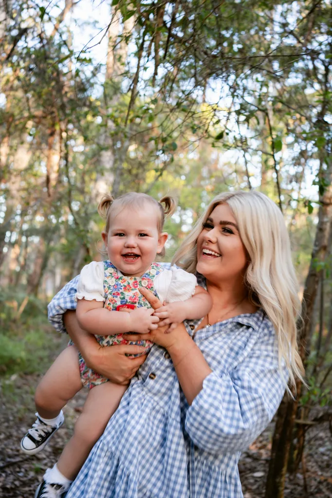 Image of mum wearing blue and white dress and holding baby wearing floral onesie