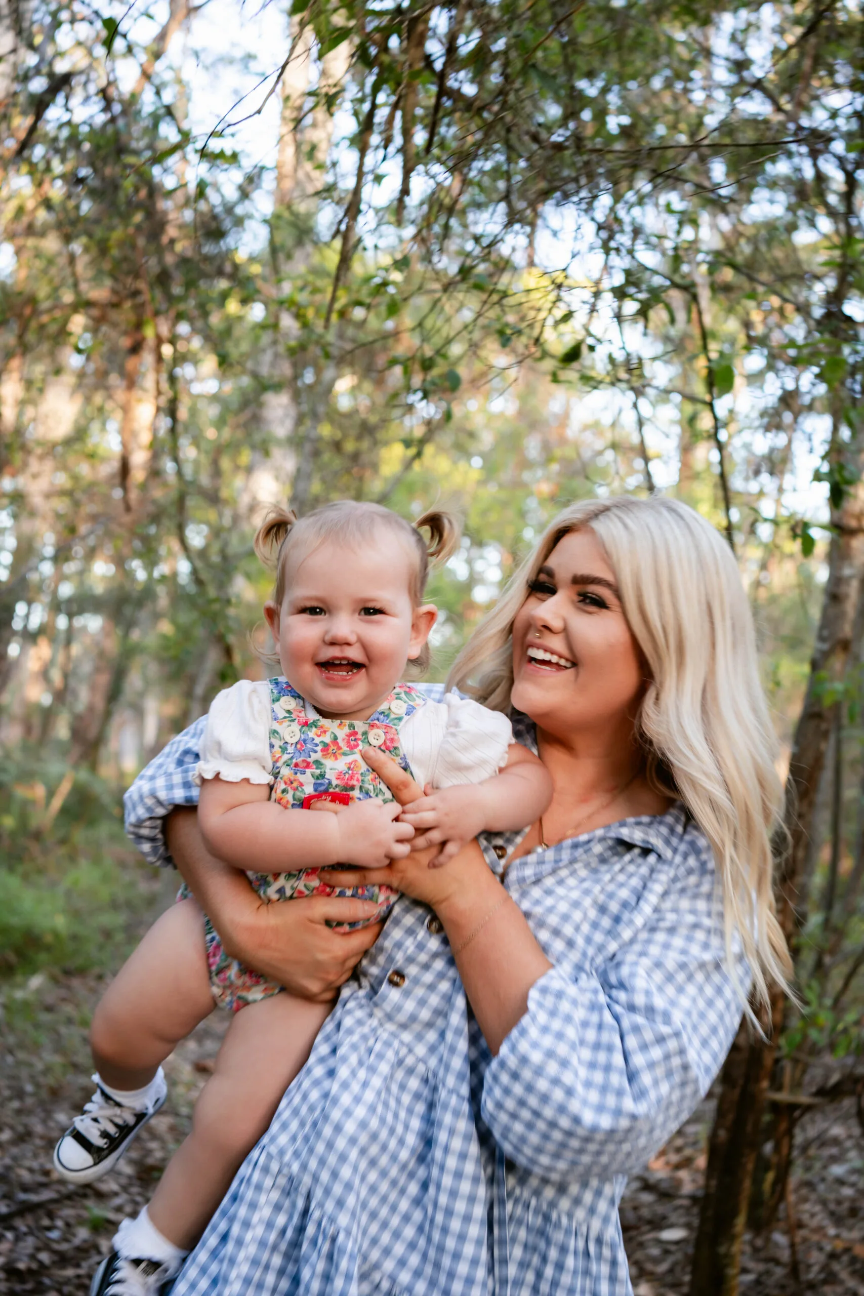 Image of mum wearing blue and white dress and holding baby wearing floral onesie