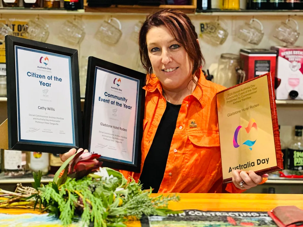 woman in orange shirt holding three awards