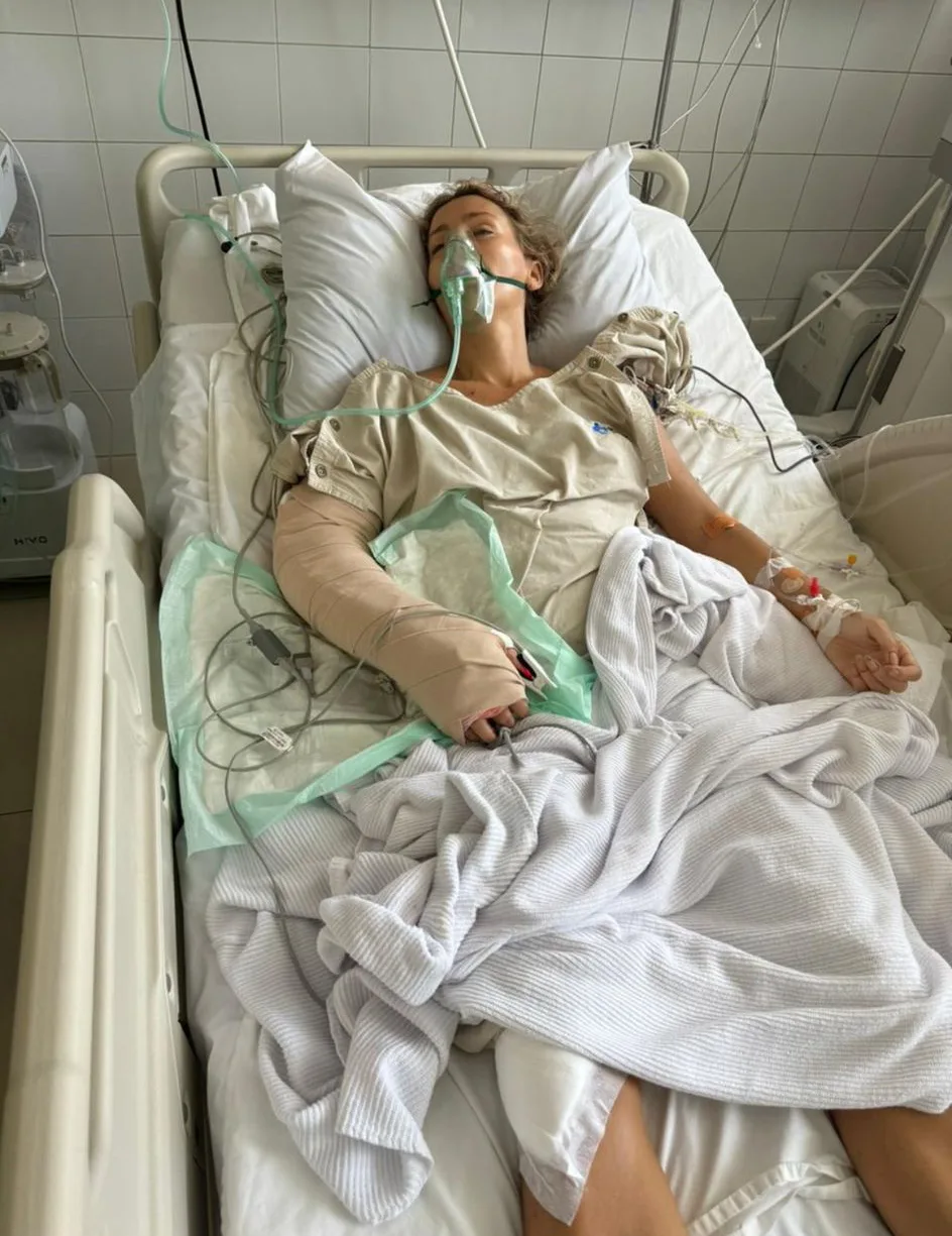Woman recovering in hospital after surgery. She is covered in wires and has a bandage 