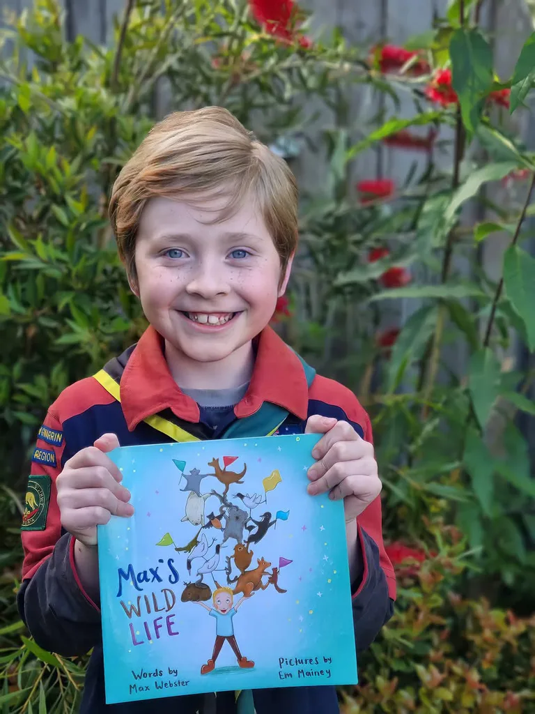 Boy holding a blue book with title Max's Wild Life