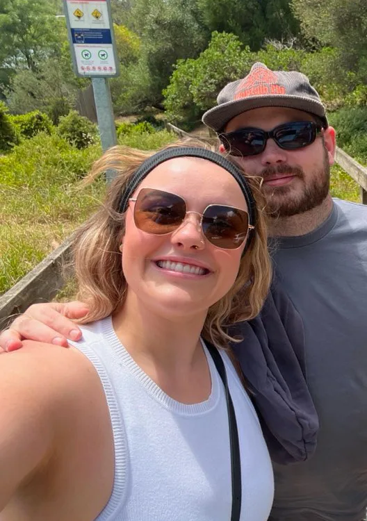 Man and woman smiling at the camera. They are both wearing sunglasses