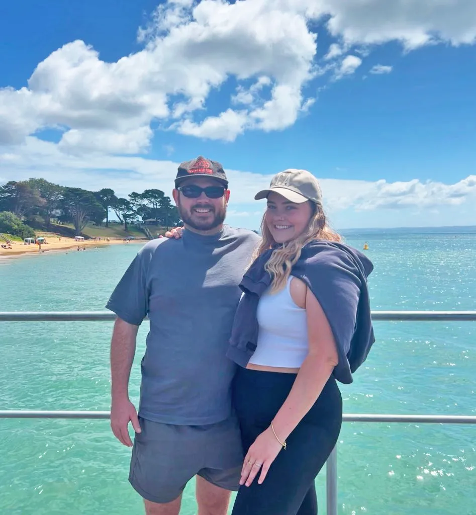 man and woman in dark coloured activewear by the water.