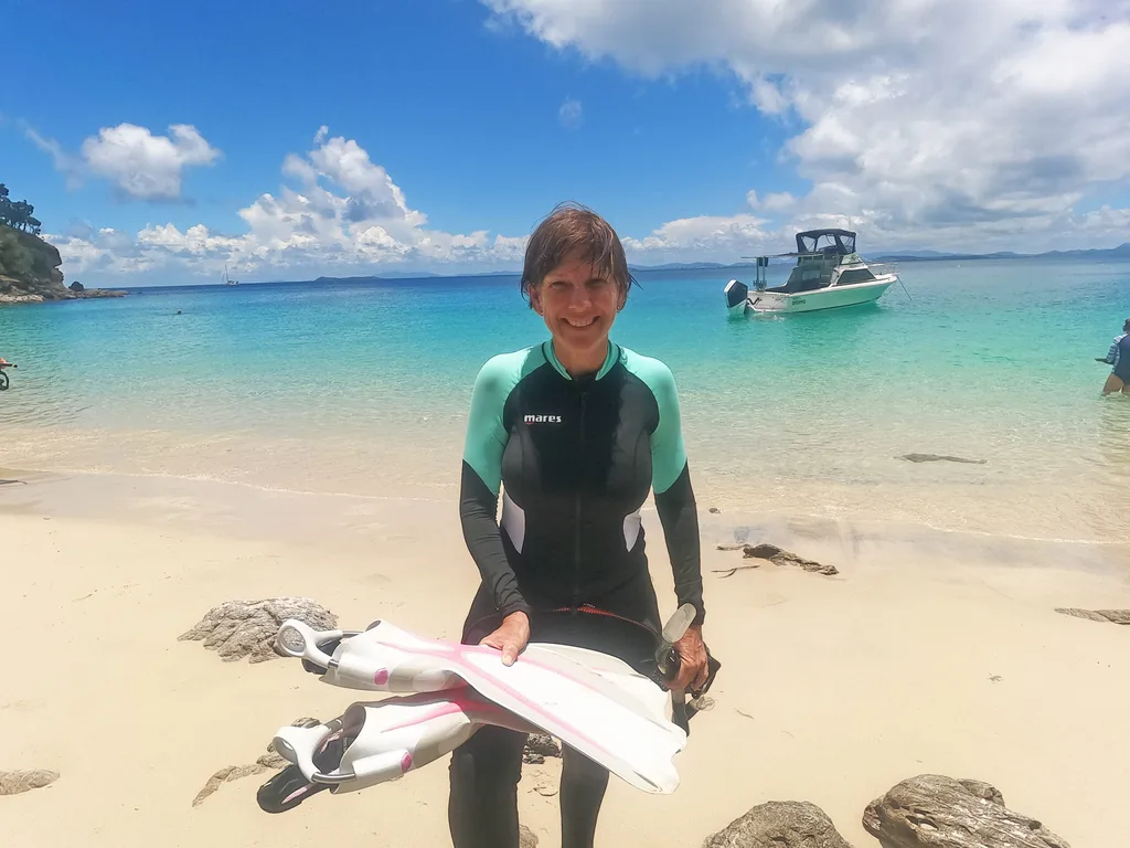 Image of woman wearing scuba diving wetsuit standing on the beach