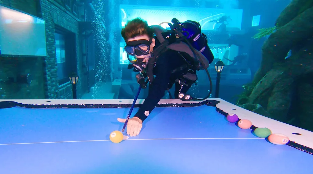 Image of woman underwater wearing scuba diving suit playing a game of pool
